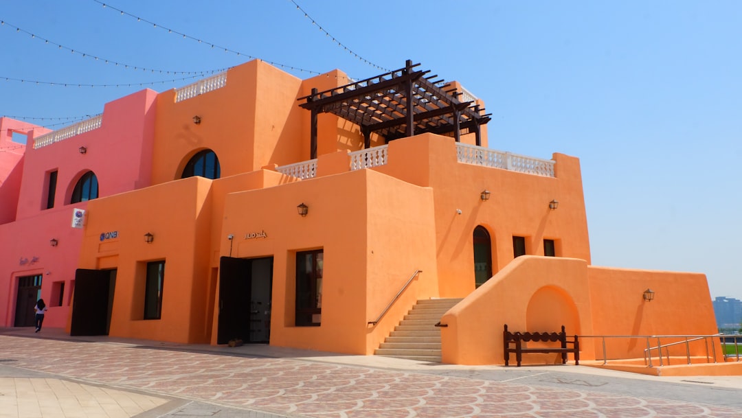 an-orange-building-with-a-wooden-bench-in-front-of-it-qq-2kbfkyy4